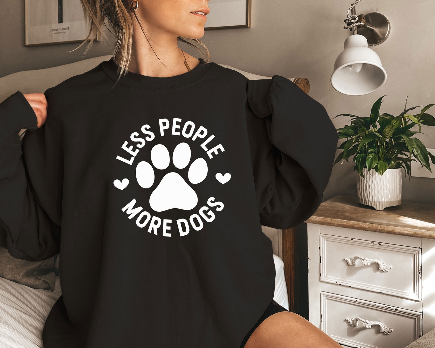 a woman sitting on a bed wearing a black shirt with a dog's paw