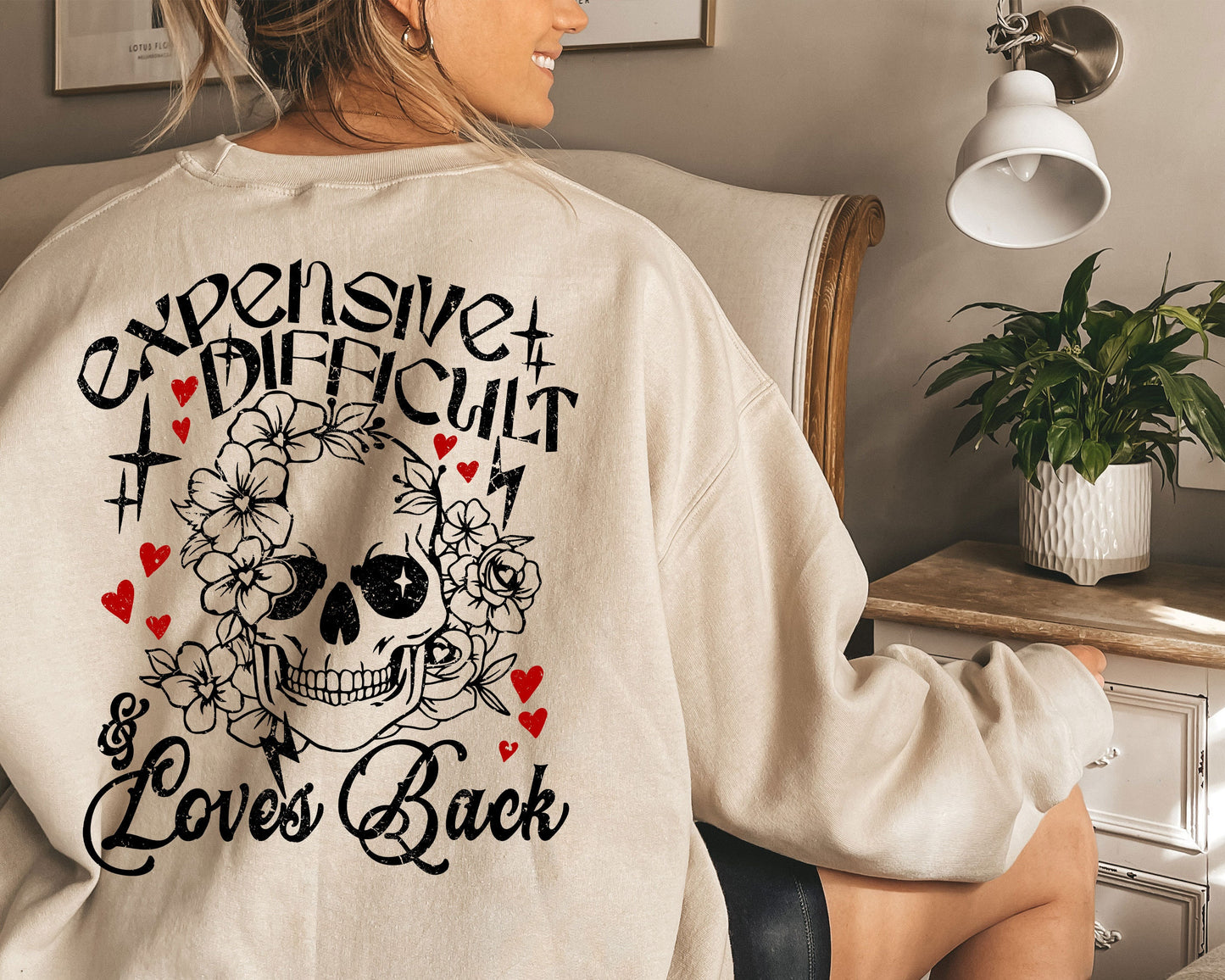 a woman sitting in a chair wearing a sweatshirt with a skull on it