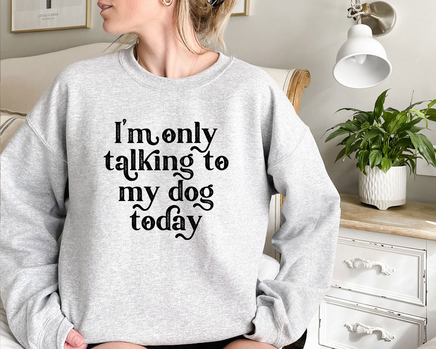 a woman sitting on a bed wearing a sweatshirt that says i'm only talking