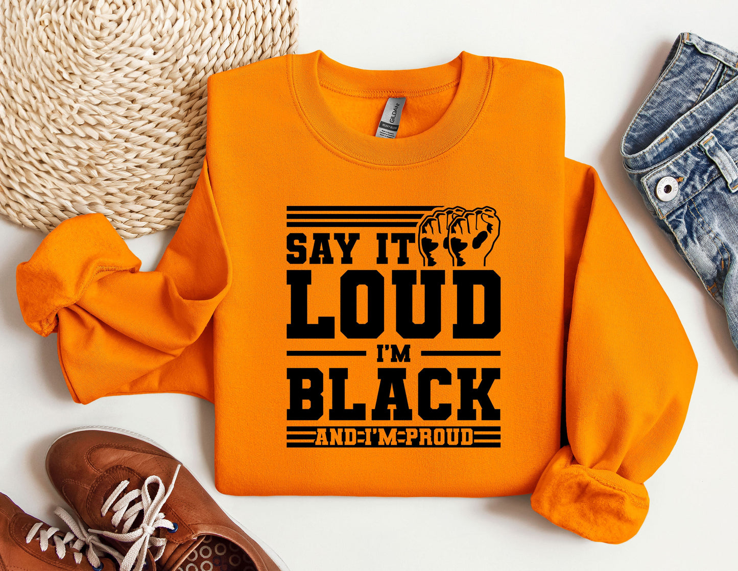 an orange sweatshirt that says say it's loud in black and a pair of