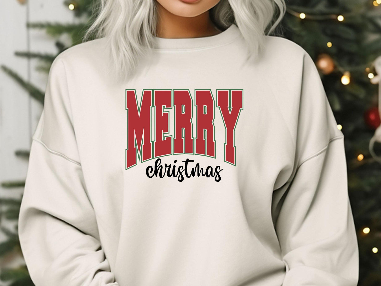 a woman wearing a merry christmas sweatshirt in front of a christmas tree