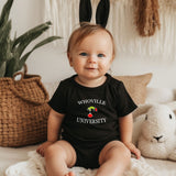 a baby sitting on a bed wearing a black shirt