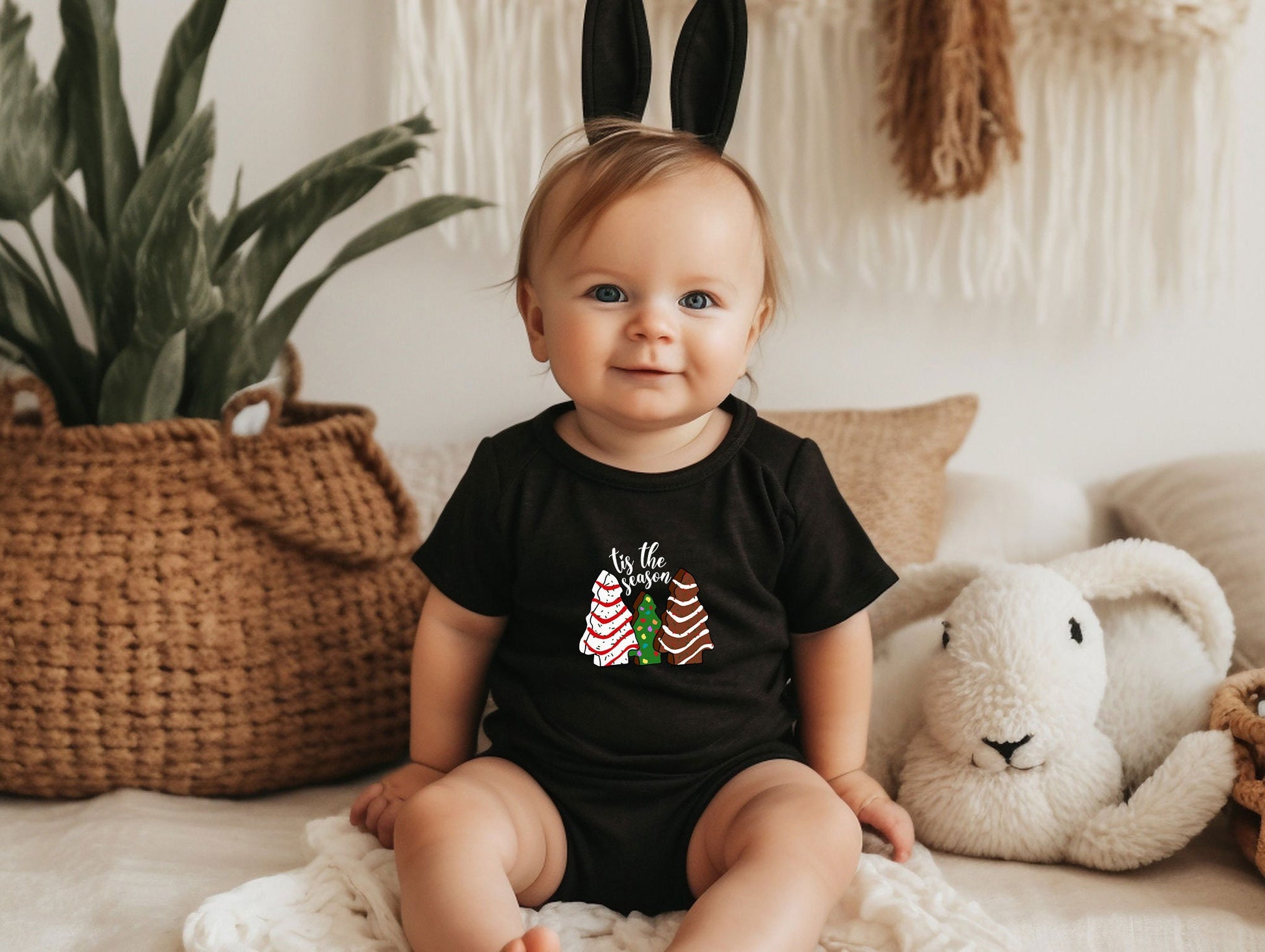 a baby sitting on a bed wearing a black shirt and bunny ears