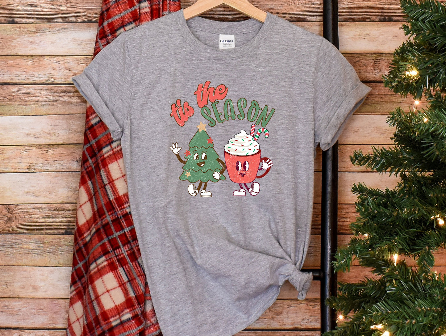 a t - shirt that says tis the season next to a christmas tree