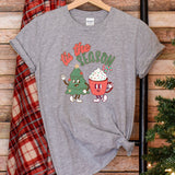 a t - shirt that says tis the season next to a christmas tree