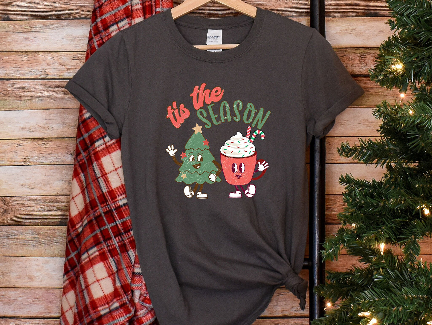 a t - shirt that says tis the season next to a christmas tree