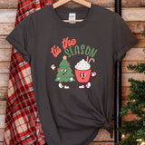 a t - shirt that says tis the season next to a christmas tree