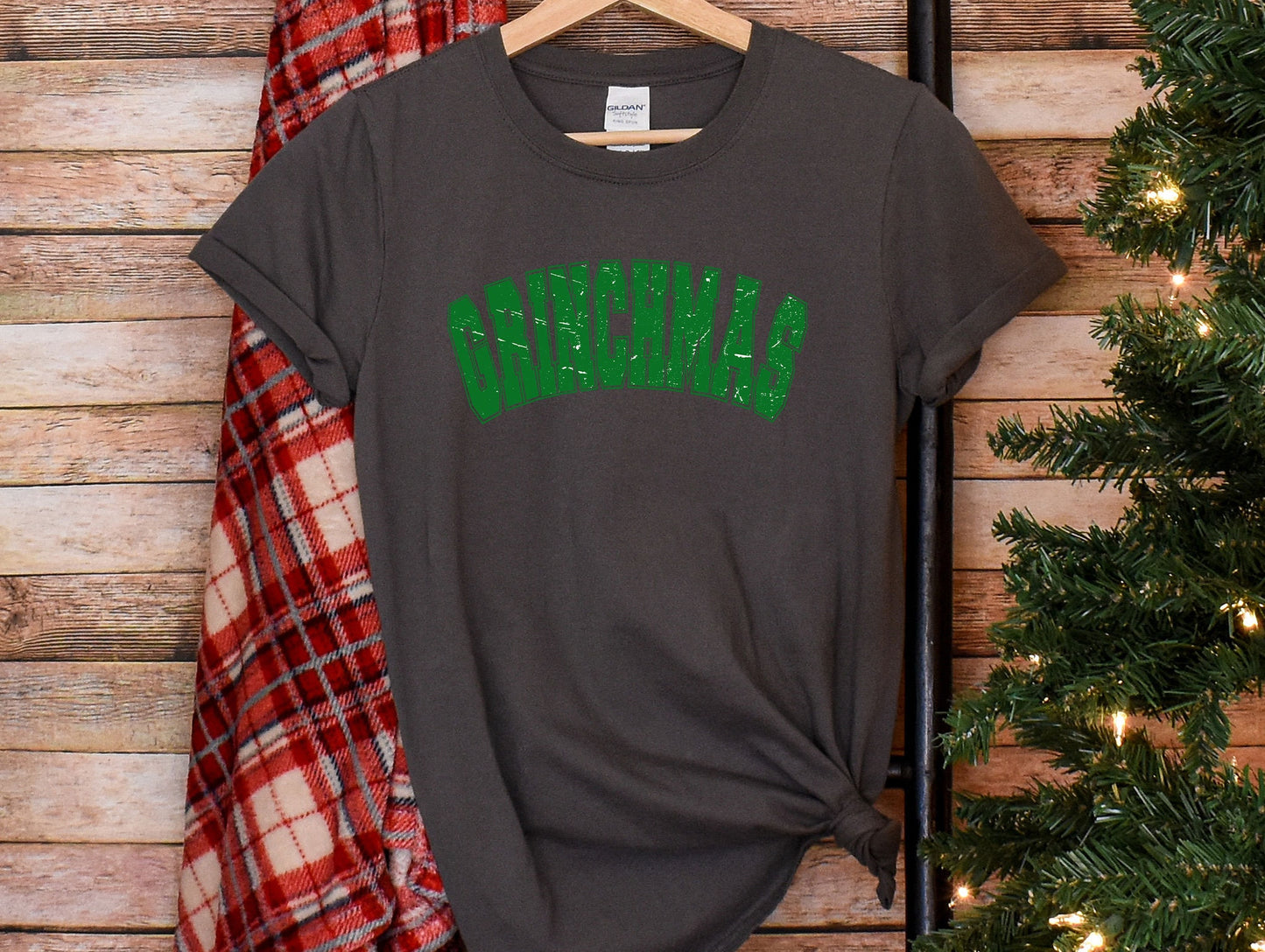 a t - shirt with the word christmas on it next to a christmas tree