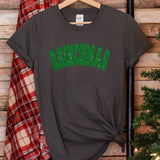 a t - shirt with the word christmas on it next to a christmas tree