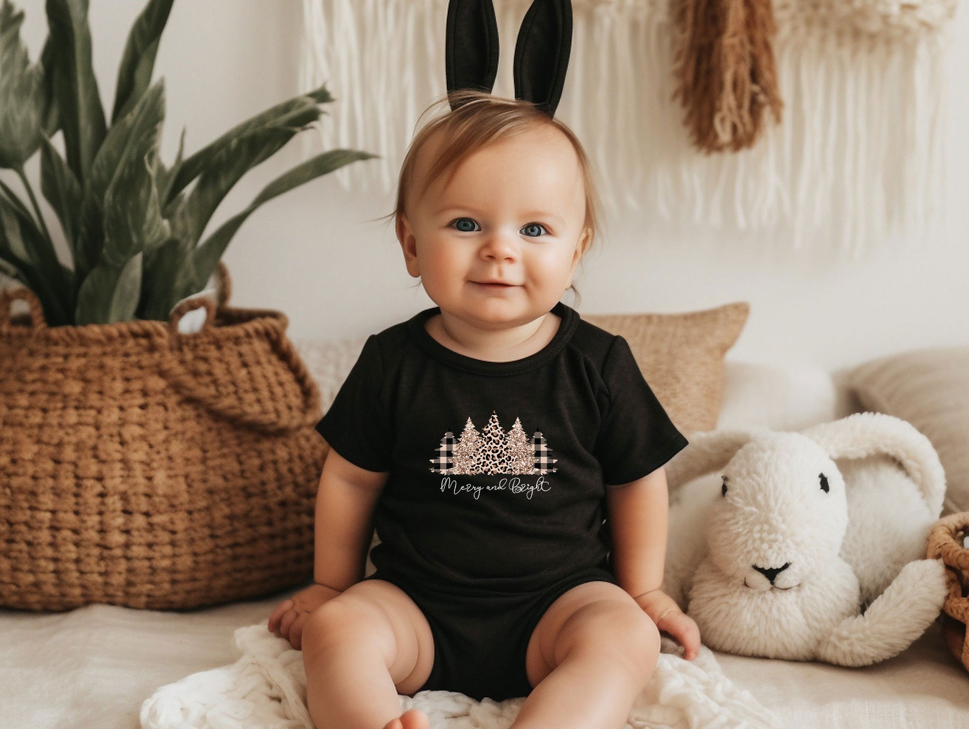 a baby sitting on a bed wearing a black shirt and bunny ears