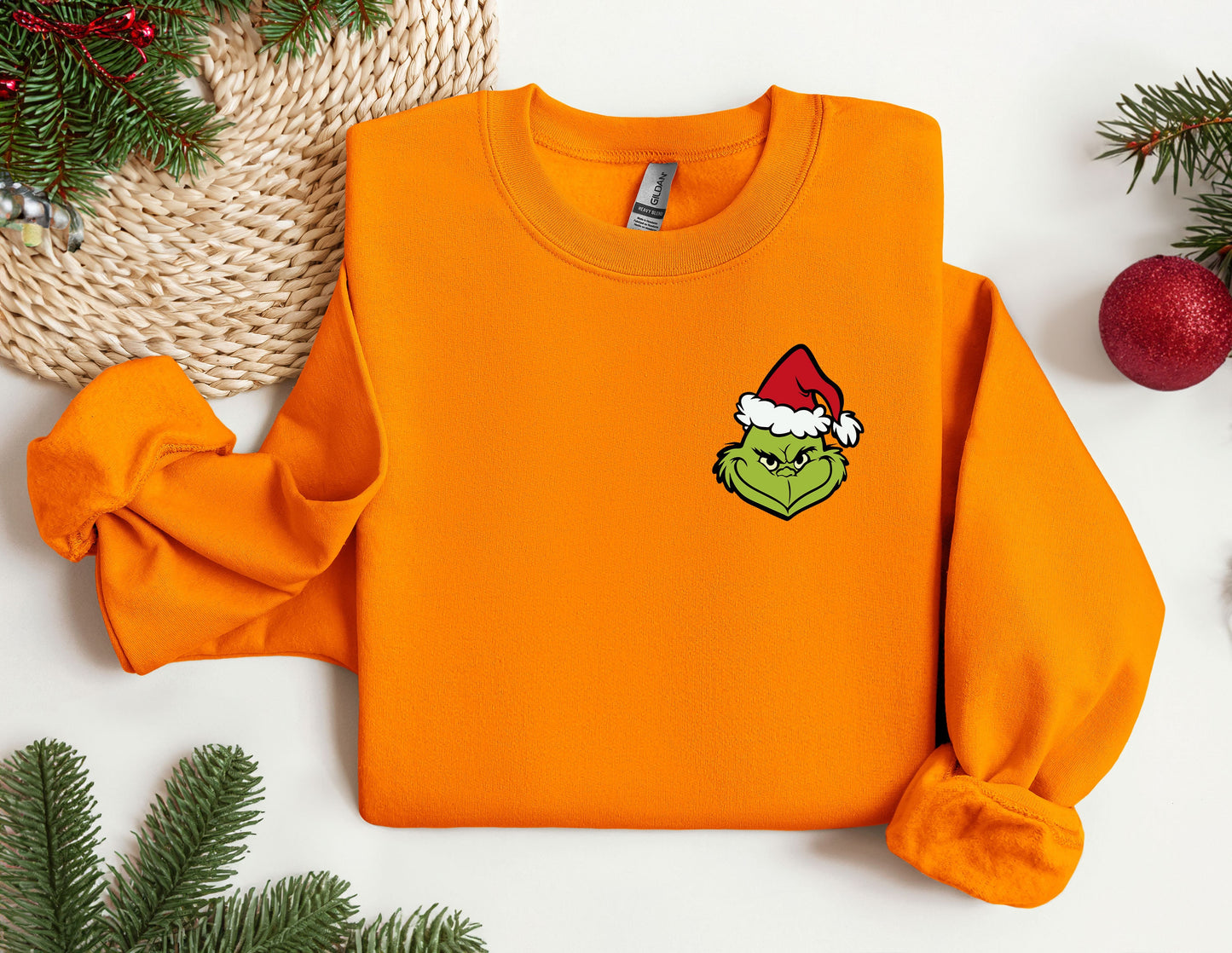 an orange sweatshirt with a green grin face on it