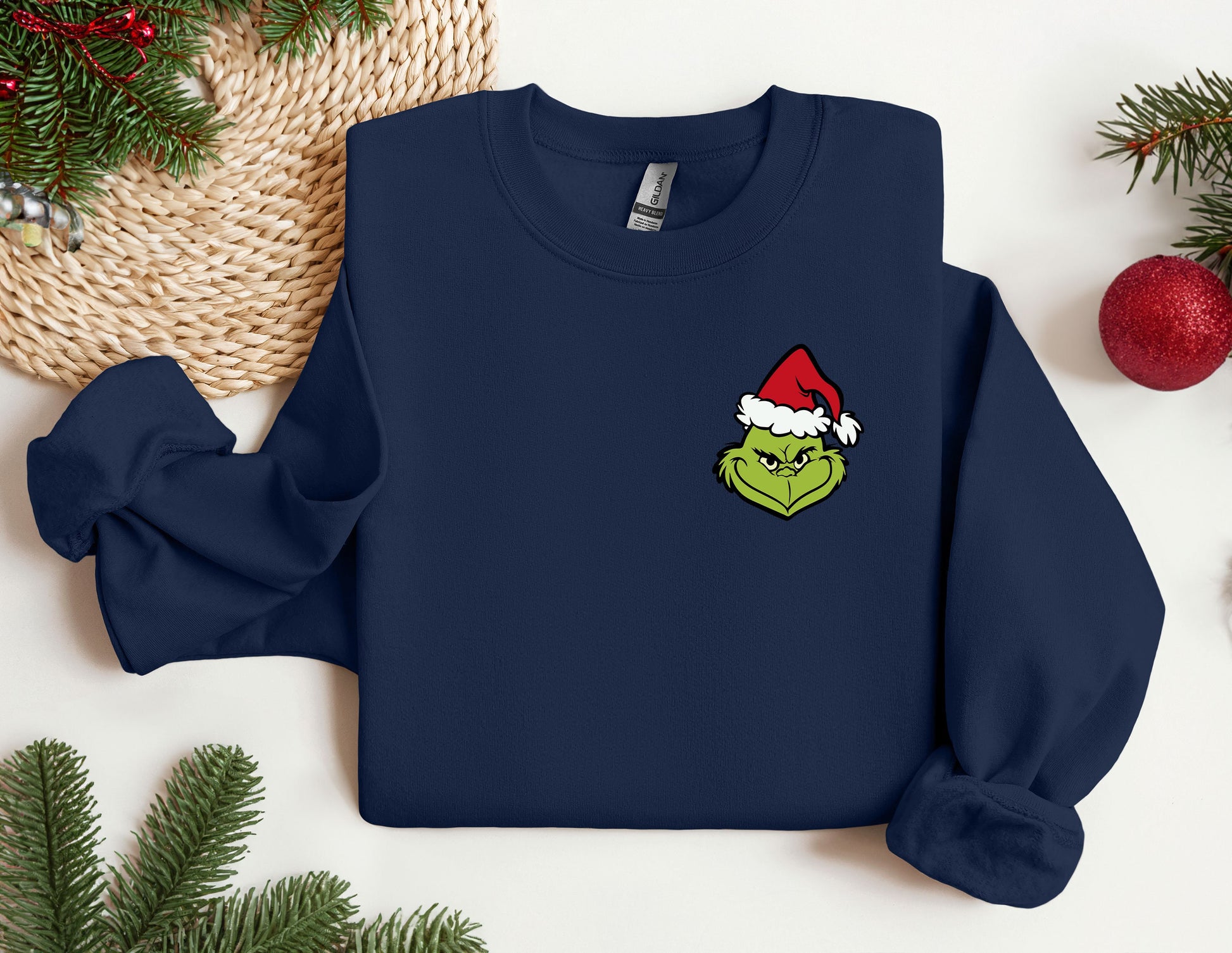 a blue sweatshirt with a green grin face wearing a santa hat