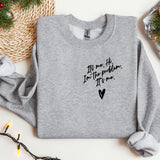 a sweater with a message on it next to a christmas tree