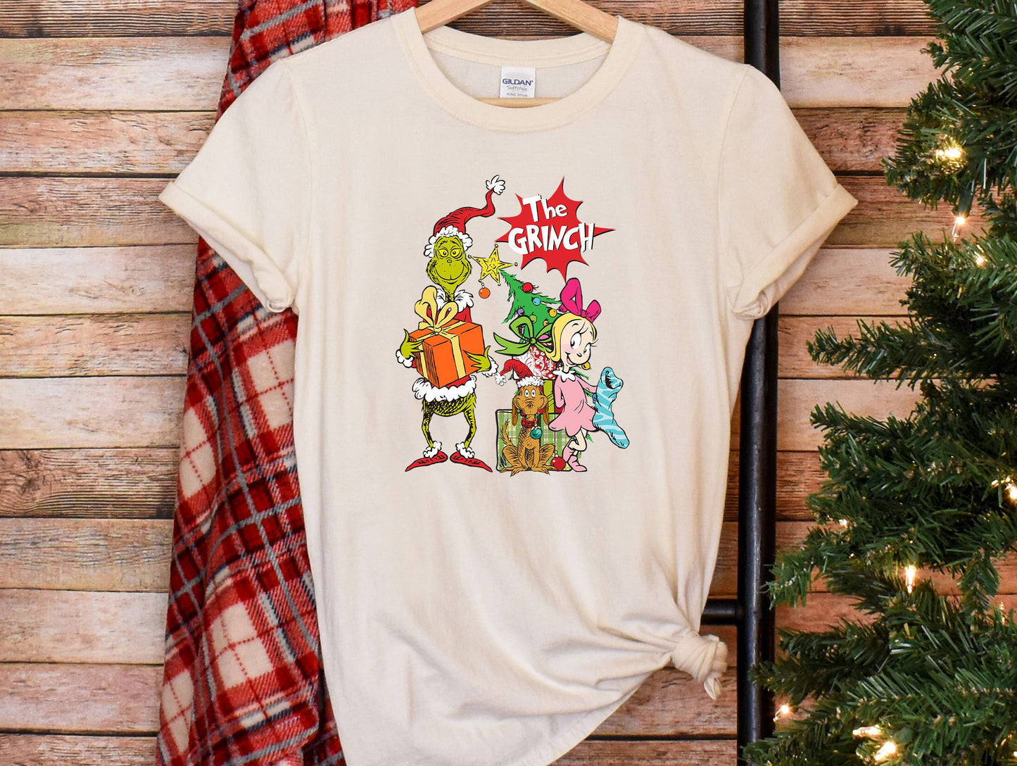 a white t - shirt with the grin on it next to a christmas tree