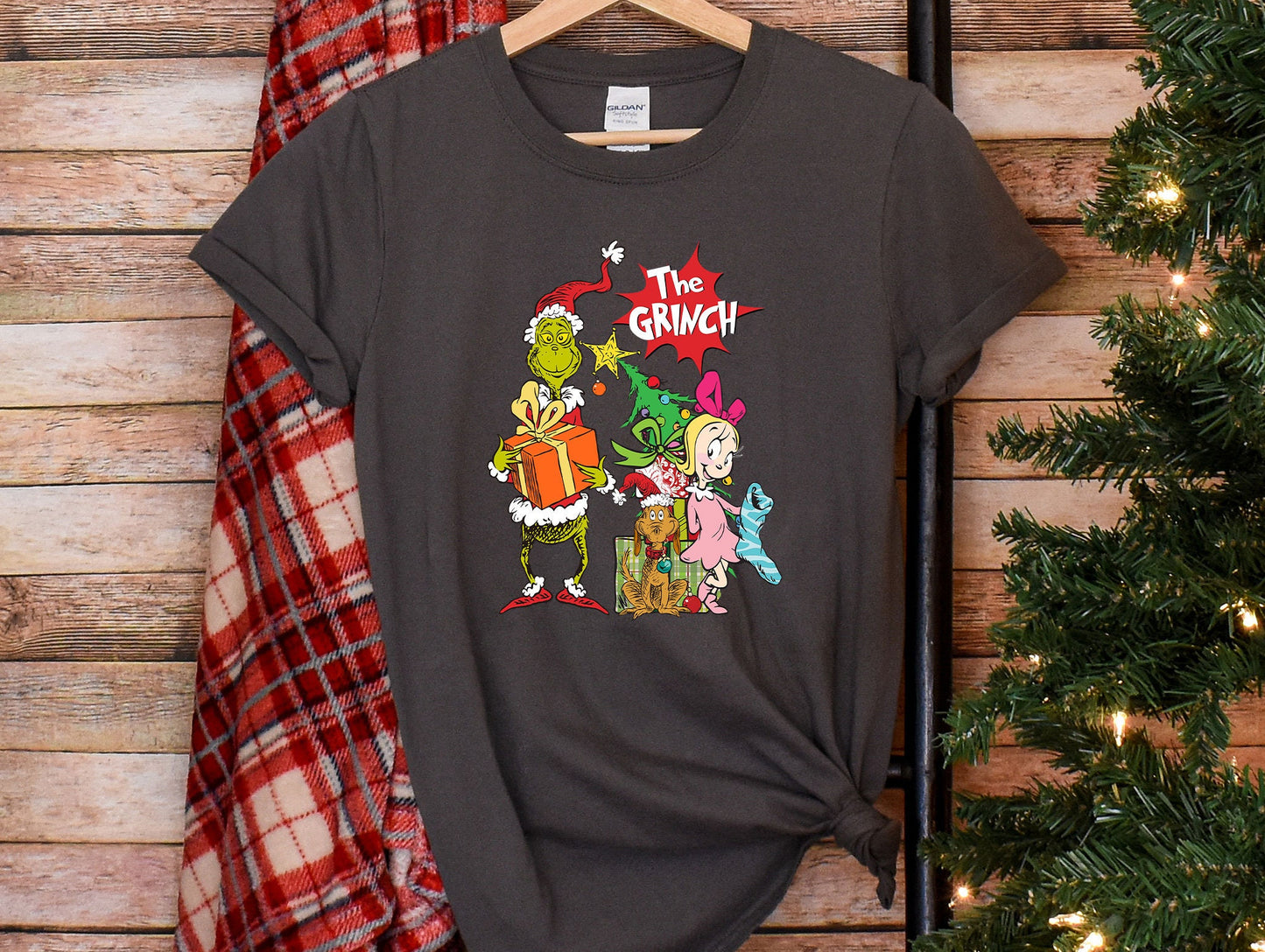 a t - shirt that says the grinch on it next to a christmas tree