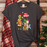 a t - shirt that says the grinch on it next to a christmas tree