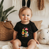 a baby sitting on a bed wearing a black shirt