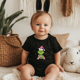 a baby sitting on a bed wearing a black shirt and bunny ears