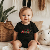 a baby sitting on a bed wearing a black shirt and bunny ears