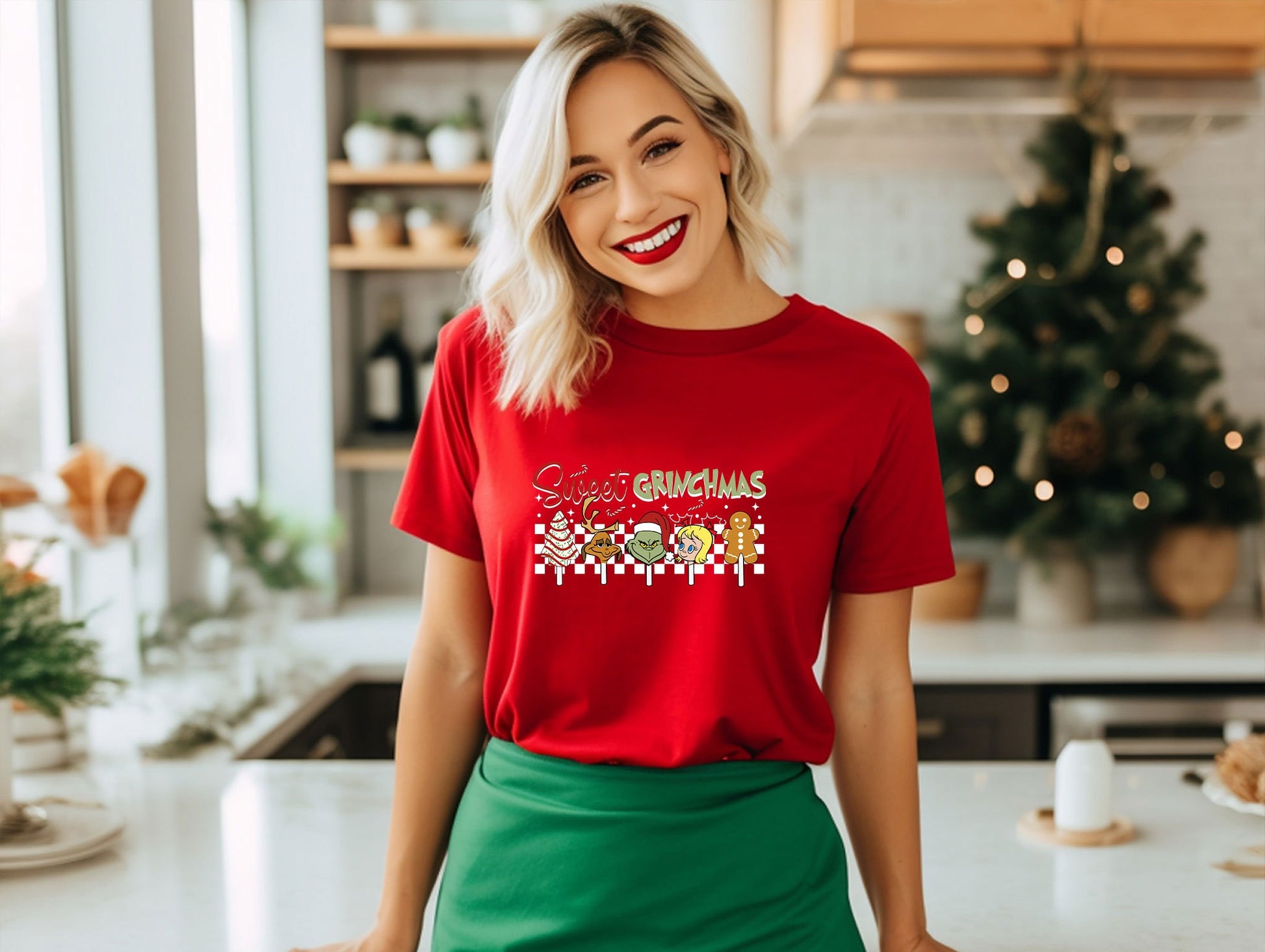 a woman standing in a kitchen wearing a red shirt and green skirt