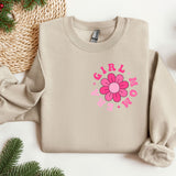 a sweater with a flower on it next to christmas decorations