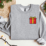 a sweater with a gift on it next to a christmas tree