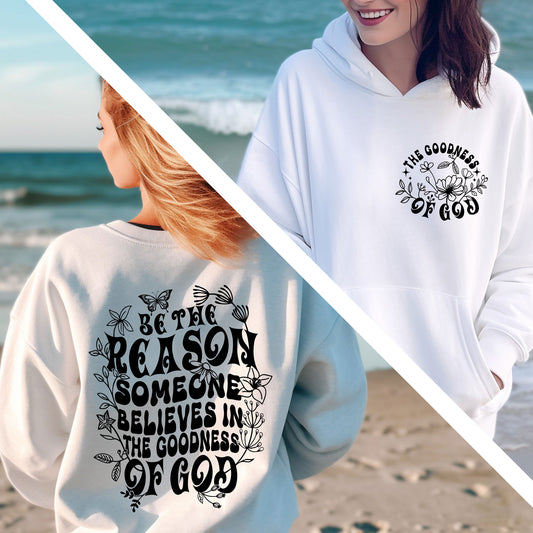 two women standing on a beach wearing sweatshirts