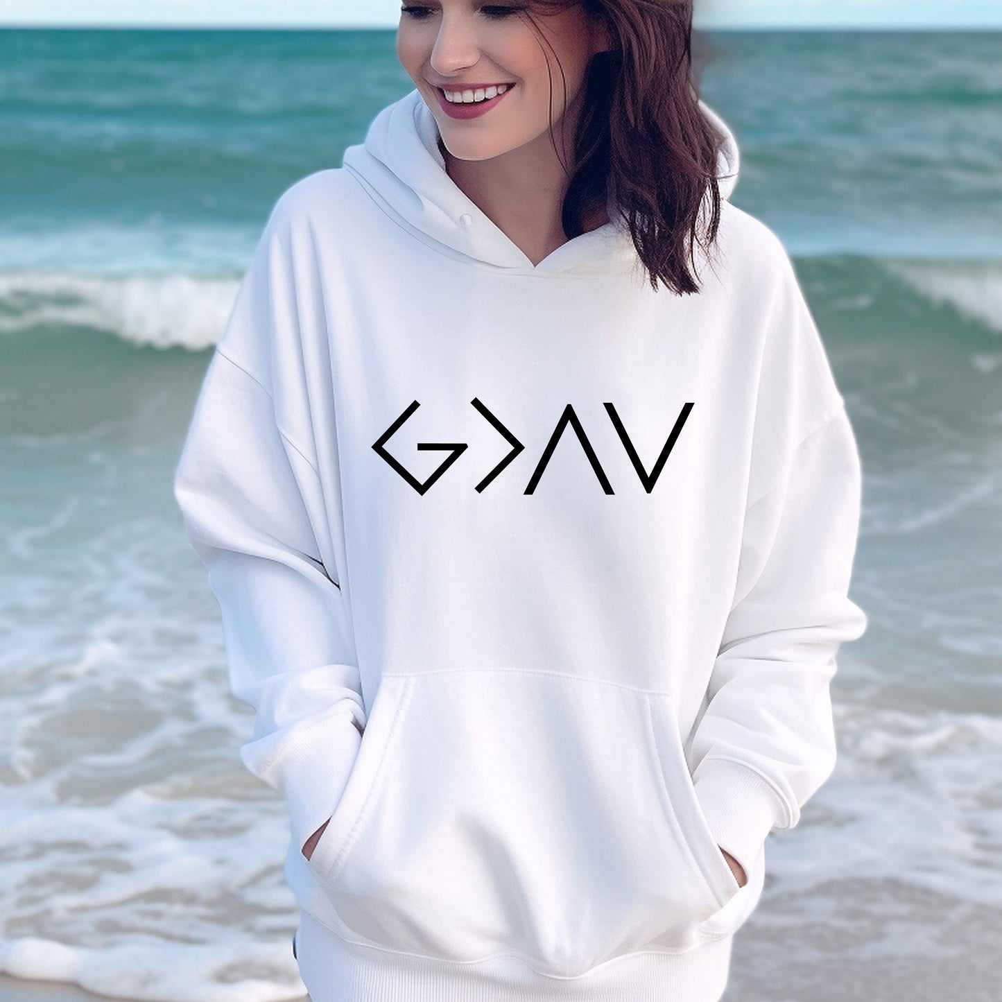 a woman standing on the beach wearing a white hoodie