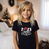 a little girl standing in front of a bed