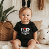 a baby sitting on a bed wearing a black shirt and bunny ears