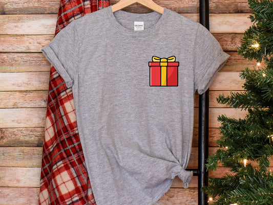 a t - shirt with a gift box on it next to a christmas tree