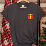 a t - shirt with a gift box on it hanging next to a christmas tree