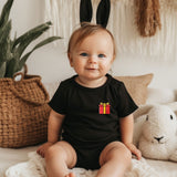 a baby sitting on a bed wearing a black shirt and bunny ears