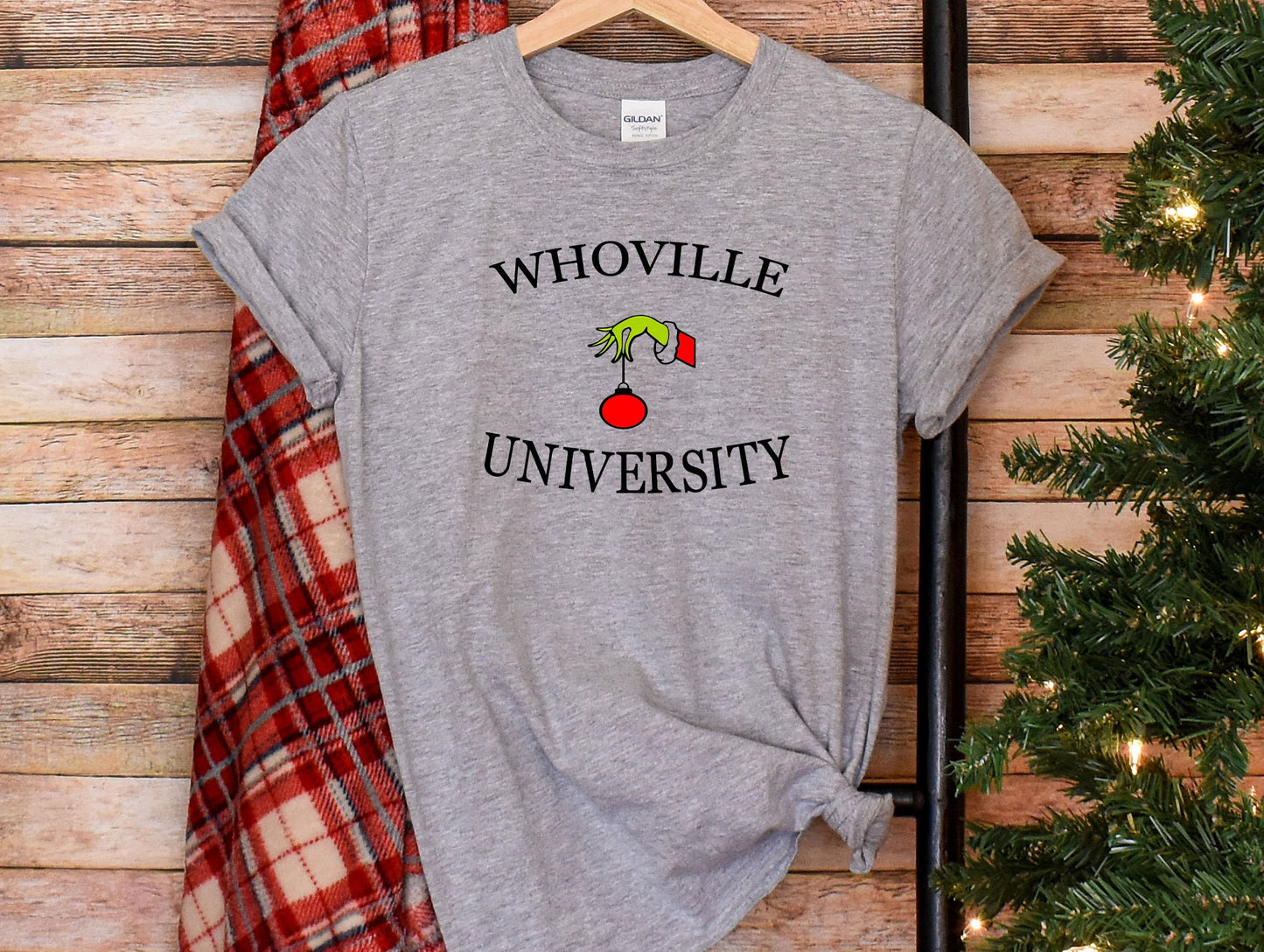 a t - shirt that says whoville university on it next to a christmas tree