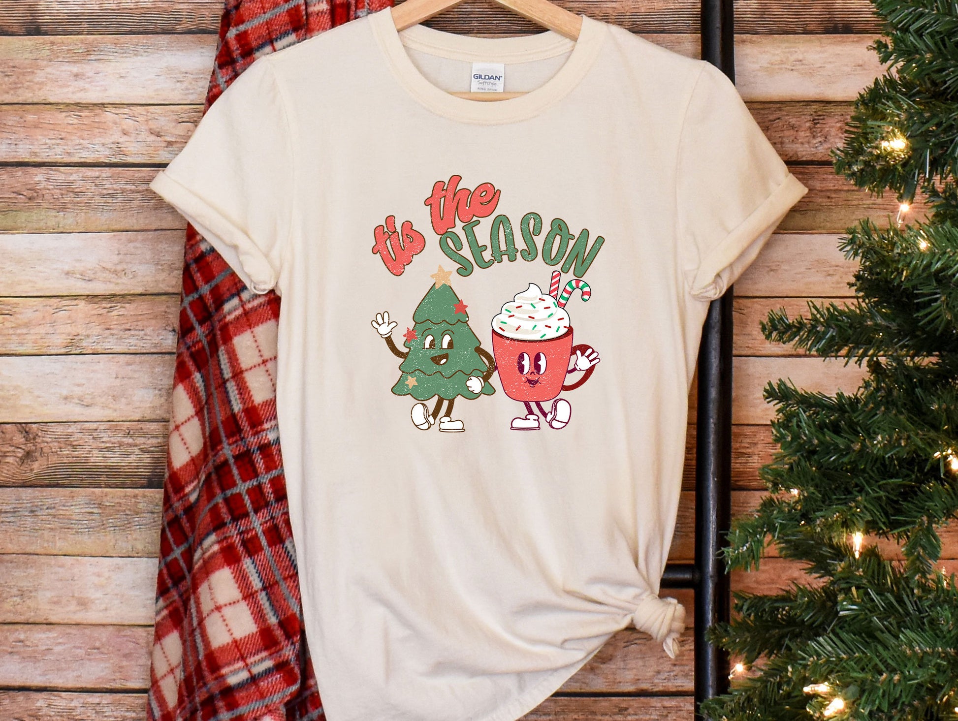 a t - shirt that says tis the season next to a christmas tree