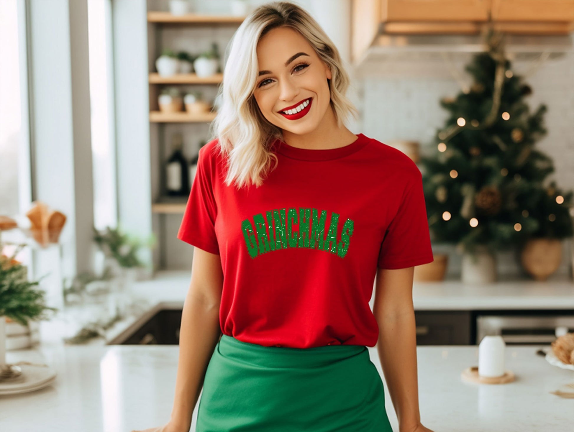 a woman standing in a kitchen wearing a red shirt and green skirt