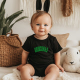 a baby sitting on a bed wearing a black shirt and bunny ears