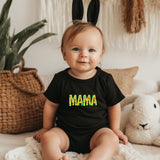 a baby sitting on a bed wearing a black shirt with the word mama printed on