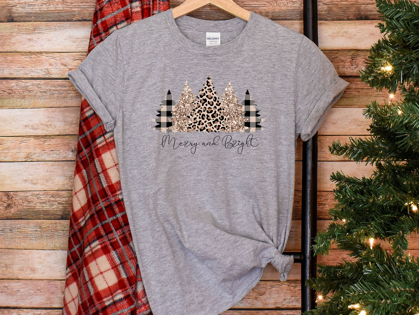 a t - shirt that says merry and bright on it next to a christmas tree