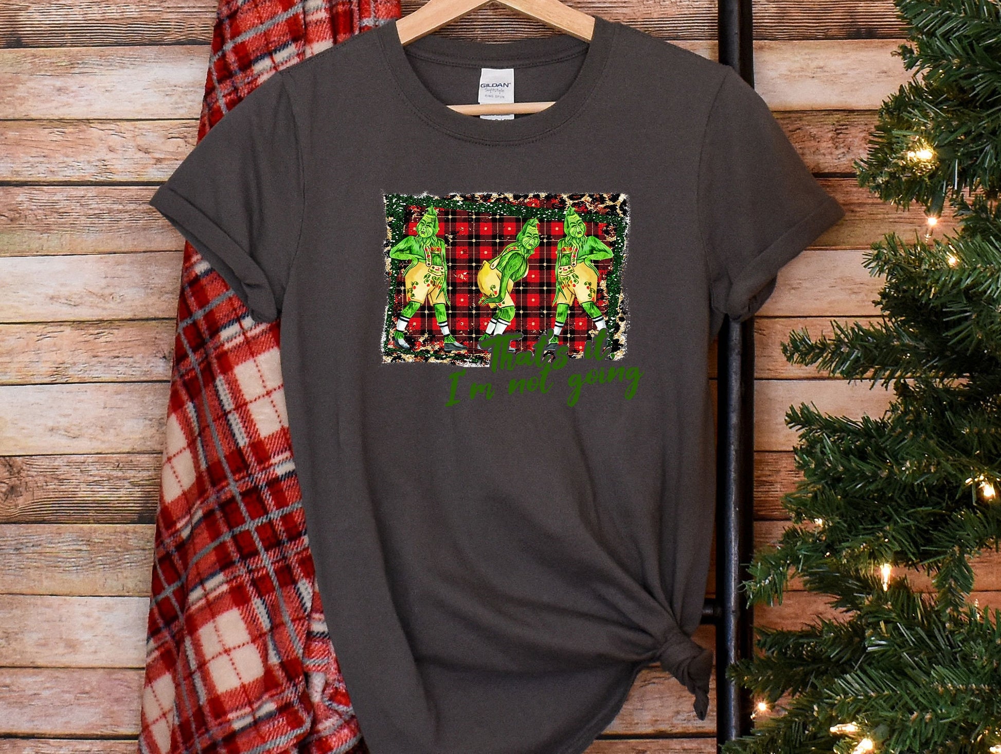 a t - shirt hanging on a wooden wall next to a christmas tree