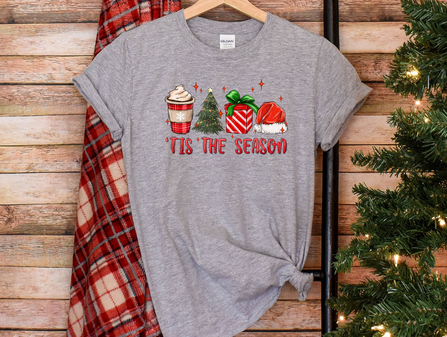 a t - shirt that says tis the season next to a christmas tree