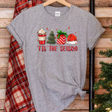 a t - shirt that says tis the season next to a christmas tree