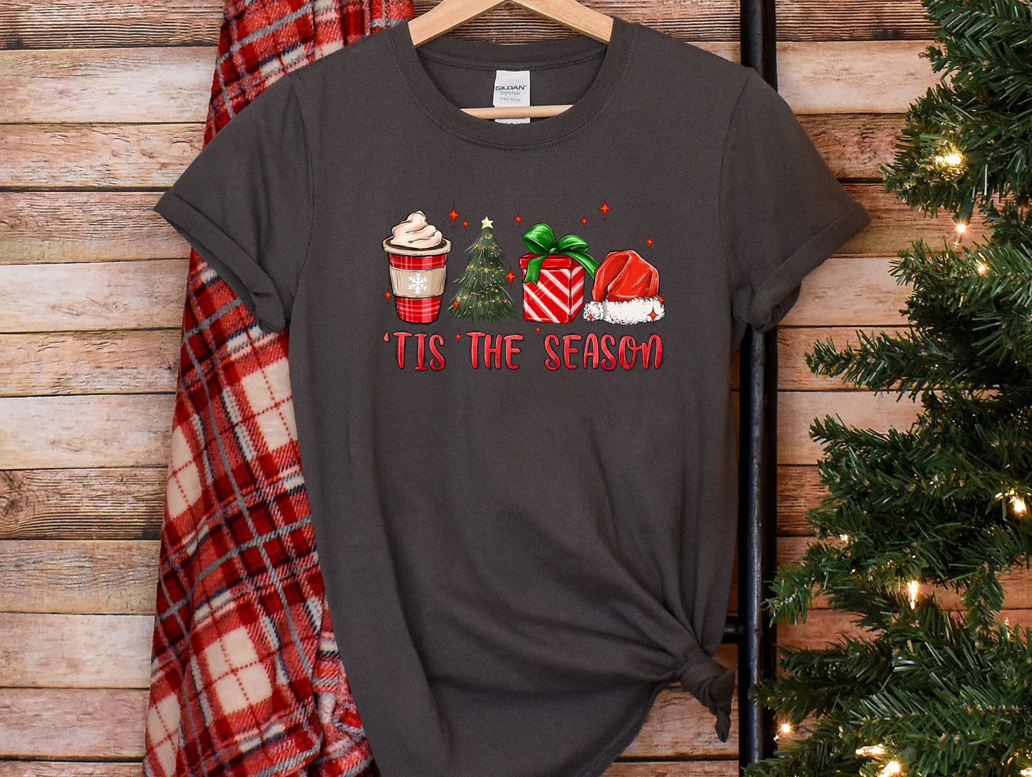 a t - shirt that says tis the season next to a christmas tree