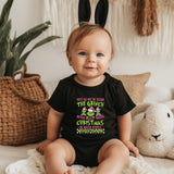 a baby sitting on a bed wearing a black shirt