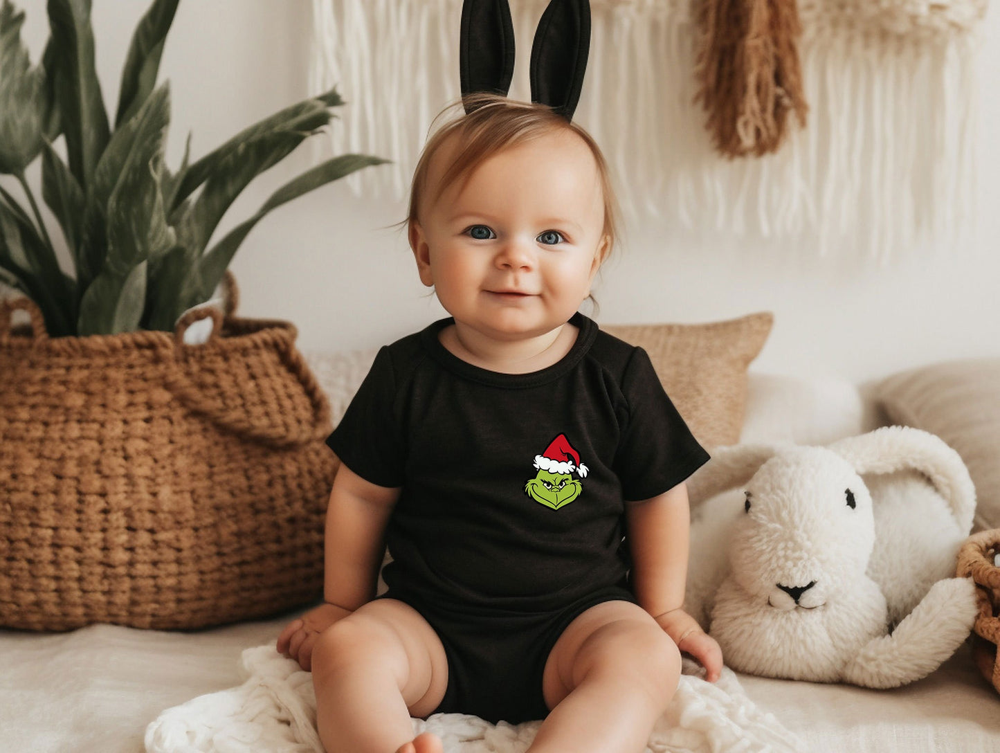 a baby sitting on a bed wearing a black shirt and bunny ears