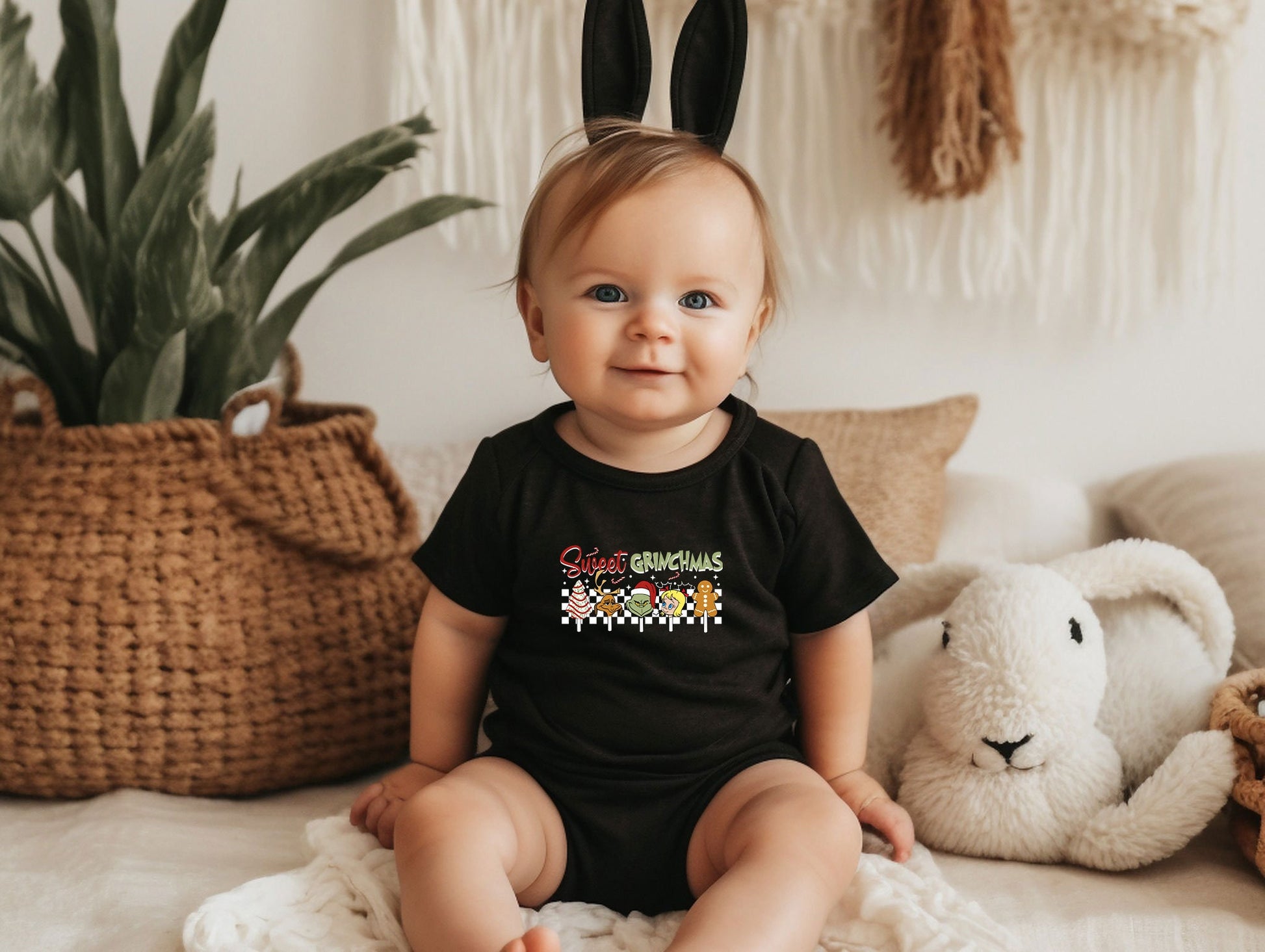 a baby sitting on a bed wearing a black shirt