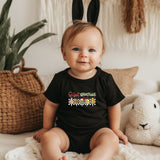 a baby sitting on a bed wearing a black shirt