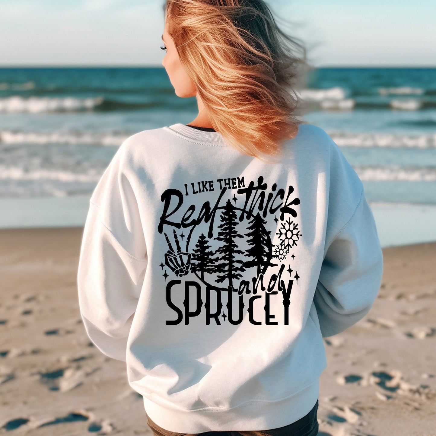 a woman standing on a beach wearing a sweatshirt