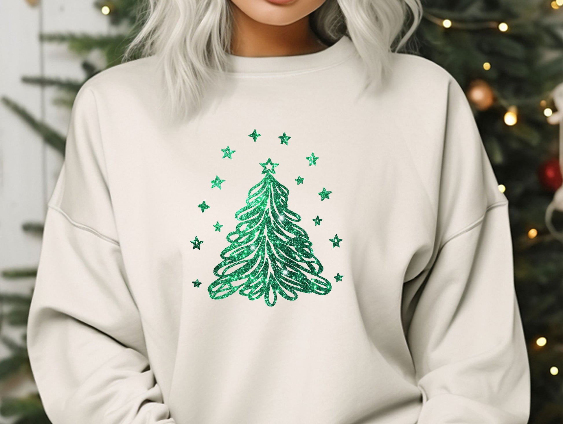 a woman wearing a white sweatshirt with a green christmas tree on it