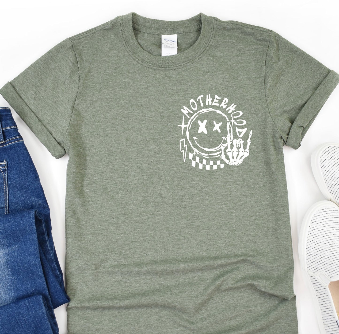 a t - shirt that says motherhood on it next to a pair of jeans